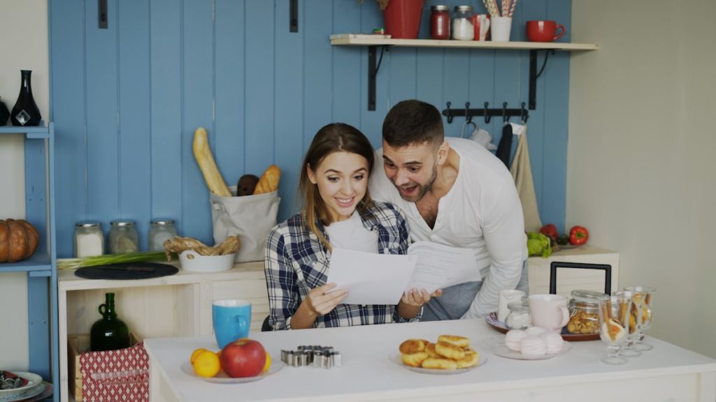 Two homeowners reviewing renovation plans and paperwork at a kitchen table